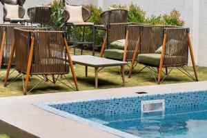 a group of chairs and a swimming pool at Trunk and Trolley, Gachibowli, A Luxury Boutique Hotel, Hyderabad in Hyderabad