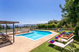 a swimming pool with chaise lounges and chairs next to at Villa Olive Grove by Villa Plus in Marathi