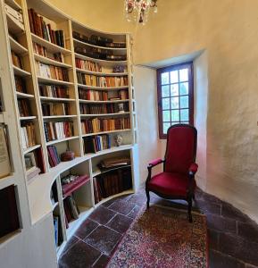a red chair in a room with book shelves at Château de Trévien in Trévien