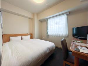 a hotel room with a bed and a desk and a television at Hotel Route-Inn Mikawa Inter in Hakusan
