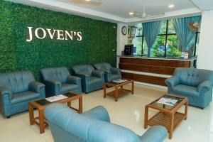 a waiting room with blue chairs and a green wall at Joven's central hotel in Bangalore
