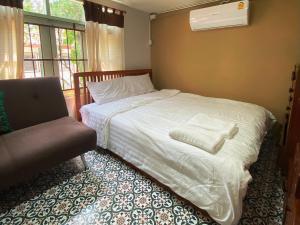 a bedroom with a white bed and a chair at เรือนเงินตรา in Ban Khlong Hok