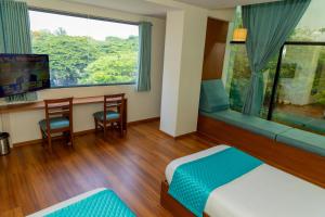 a hotel room with a bed and a desk and a window at Joven's central hotel in Bangalore +30 photos