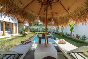a patio with a table and chairs and an umbrella at LYS Home in Jimbaran