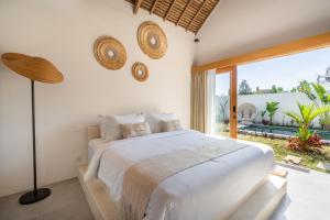 a bedroom with a white bed and a large window at LYS Home in Jimbaran