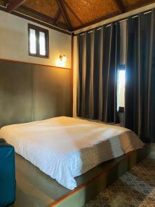 a bedroom with a large bed with a window at เรือนเงินตรา in Ban Khlong Hok +1 photo