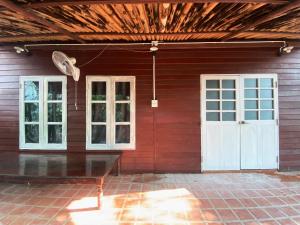 a red house with white doors and a table outside at เรือนเงินตรา in Ban Khlong Hok