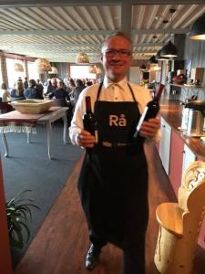 a man in an apron holding two wine bottles at Bergsjøstølen Fjellstue in Bergsjostolen