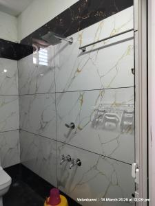 a bathroom with a shower with marble tiles at Hotel Grand Arputha in Velankanni +23 photos