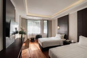 a hotel room with two beds and a television at Bentani Hotel & Residences Cirebon in Cirebon +11 photos