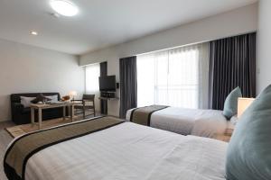 a hotel room with two beds and a desk at Kantary Hotel And Serviced Apartment, Amata, Bangpakong in Ban Tamru
