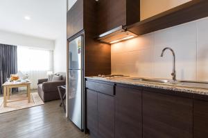 a kitchen with wooden cabinets and a stainless steel refrigerator at Kantary Hotel And Serviced Apartment, Amata, Bangpakong in Ban Tamru