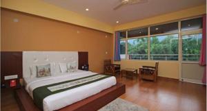 a bedroom with a large bed and a desk and window at Red carpet hotel in Kangra