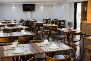 a dining room with tables and chairs and a television at Hotel Real Executive in Aparecida de Goiânia