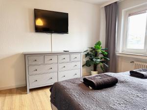 a bedroom with a dresser with a flat screen tv on the wall at 3 Zimmer Apartment mit Garten in Wuppertal