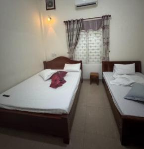 two twin beds in a room with a window at Long Khang Hotel in Quang Tri