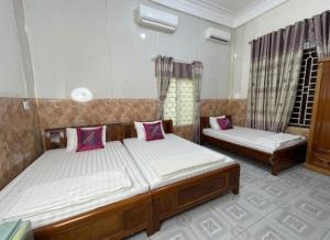 a bedroom with two beds with pink pillows at Long Khang Hotel in Quang Tri