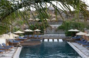 a swimming pool with lounge chairs and umbrellas at Elounda Orama by GHH in Elounda
