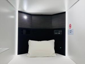 a bed with a white pillow in a room at Capsule Hotel Suzumoriya in Tokyo