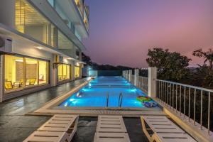 a swimming pool on the balcony of a house at night at ALAYA STAYS Midpoint UMA Pet-Friendly 7 BHK Villa Pool and Entertainment in Chicalim