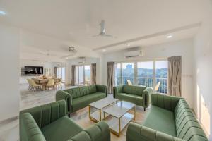 a living room with green couches and a table at ALAYA STAYS Midpoint UMA Pet-Friendly 7 BHK Villa Pool and Entertainment in Chicalim +75 photos