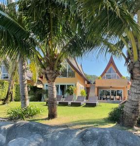 a house with palm trees in front of it at Beachfront Pool Villa in Ko Chang