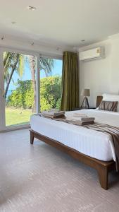 a bedroom with a large bed with a large window at Beachfront Pool Villa in Ko Chang