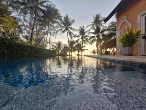 a swimming pool next to a house with palm trees at Beachfront Pool Villa in Ko Chang