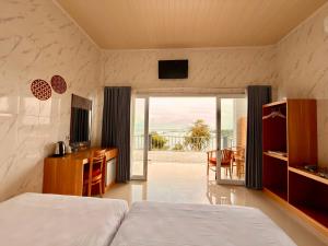 a bedroom with a bed and a desk and a balcony at Prasi Sunrise Sea View in Nusa Penida