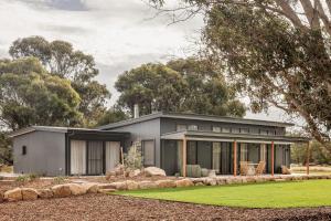 a gray house with a green lawn in front of it at Wilyabrup Waters Retreat in Wilyabrup