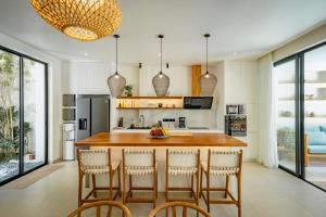 a kitchen with a large island with bar chairs at Casa Capucine Uluwatu in Uluwatu
