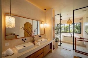 a bathroom with two sinks and a large mirror at Casa Capucine Uluwatu in Uluwatu