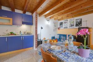 a kitchen with blue cabinets and a table with flowers on it at Vida Boa Apartments in Nago-Torbole