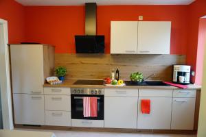 a kitchen with white cabinets and an orange wall at Zum Schlafwandler in Mengerschied