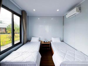 two beds in a room with two windows at ANORA Homestay in Vũng Liêm +24 photos