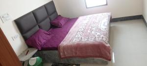 a small bed with purple sheets and purple pillows at SK Hotel Raisingh Nager in Rāisinghnagar