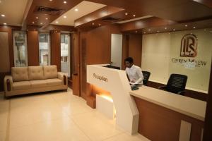 a man sitting at a counter in a lobby at Green View Suites in Kalyānpur
