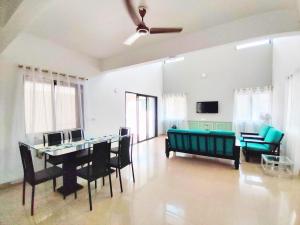 a living room with a couch and a table and chairs at MARIGOLD VILLA Il 3BHK II AC II POOL II in Lonavala
