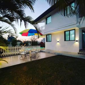 a patio with chairs and an umbrella in front of a house at MARIGOLD VILLA Il 3BHK II AC II POOL II in Lonavala