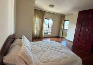 a bedroom with a bed with a wooden floor and windows at Luxury Oasis-May Real Estate Apartments in Addis Ababa