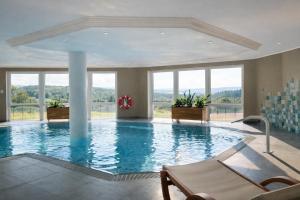 a large swimming pool in a building with windows at Hotel Kammweg in Grossbreitenbach