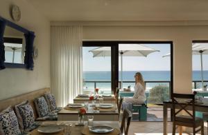 a woman sitting in a living room with a view of the ocean at Shalom-self catering apartment in St Francis Bay