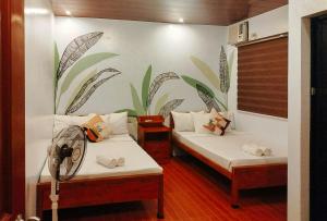 two beds in a room with a mural on the wall at RedDoorz at Balai Malinawon Siargao in General Luna