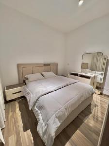 a white bedroom with a large bed and a mirror at دقيقه للبحيره أقامه فندقيه مدينتي بريفادو madinaty privado in Madinaty