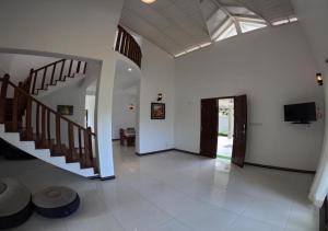 a living room with a staircase and a flat screen tv at Shade Villa in Galle
