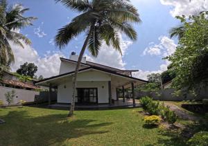 a palm tree in front of a house at Shade Villa in Galle