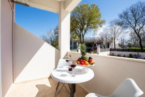 a small white table on a balcony with a bowl of fruit at Veneti Apartments - Corfu Serene Getaways in Sidari
