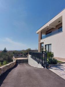 a driveway leading to a white building at Holiday house VILLA PATRICK with pool, jacuzzi and sauna in Kornić