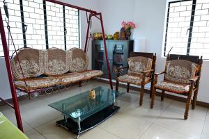 a living room with two chairs and a glass table at Giri Darshini Homestay - 3BH, Simple Rooms with Pool & Private Falls in Chikmagalūr