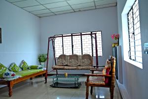 a living room with a couch and a table at Giri Darshini Homestay - 3BH, Simple Rooms with Pool & Private Falls in Chikmagalūr